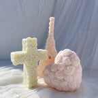Rose heart and floral cross castings beside tall decorative candles