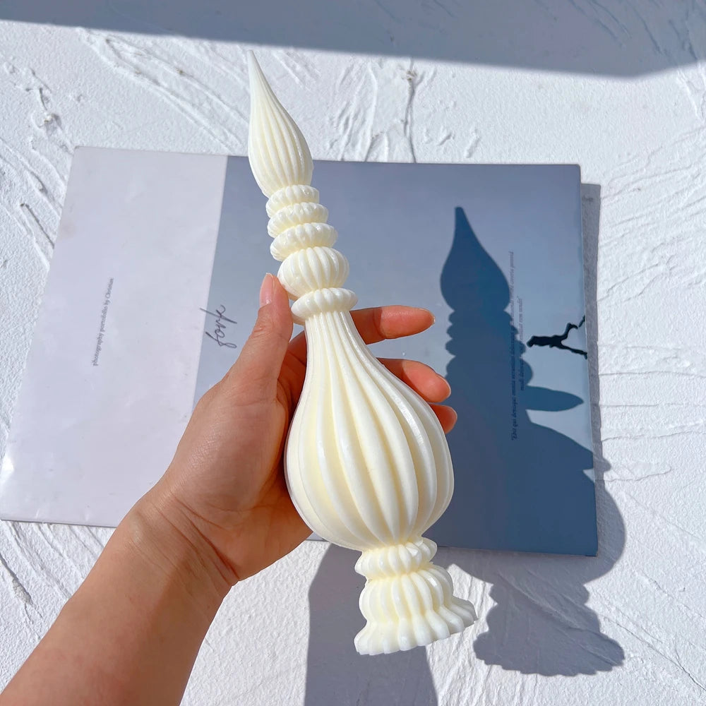 Ribbed finial casting held in a hand showing its bulb and narrow neck