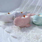 Two whale-shaped decorative castings resting on soft white surface