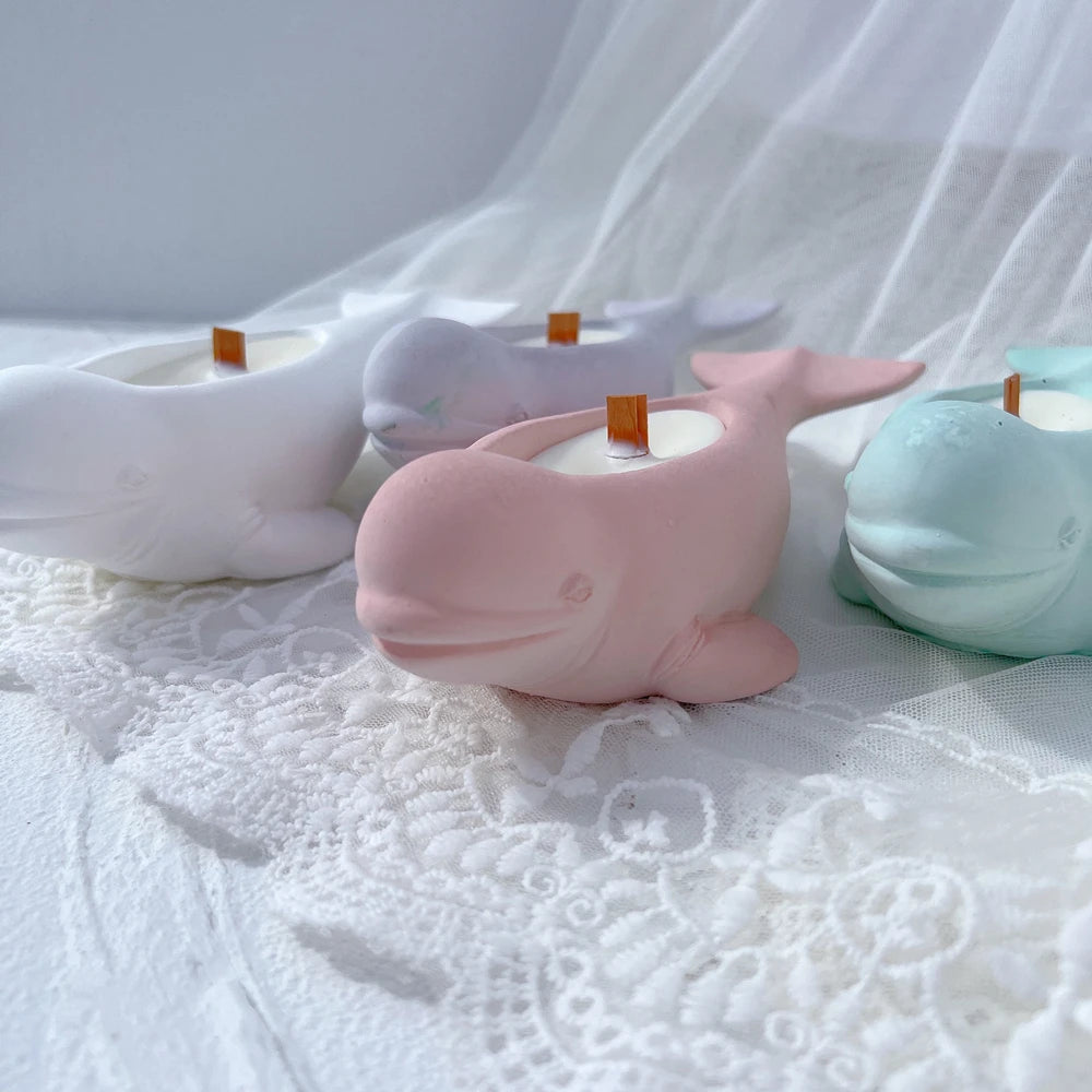 Two whale-shaped decorative castings resting on soft white surface