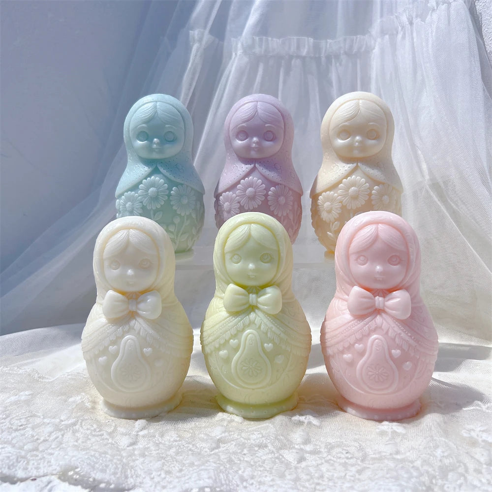 Two rows of rounded nesting doll candle castings with headscarves and patterned fronts