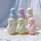 Two rows of rounded nesting doll candle castings with headscarves and patterned fronts