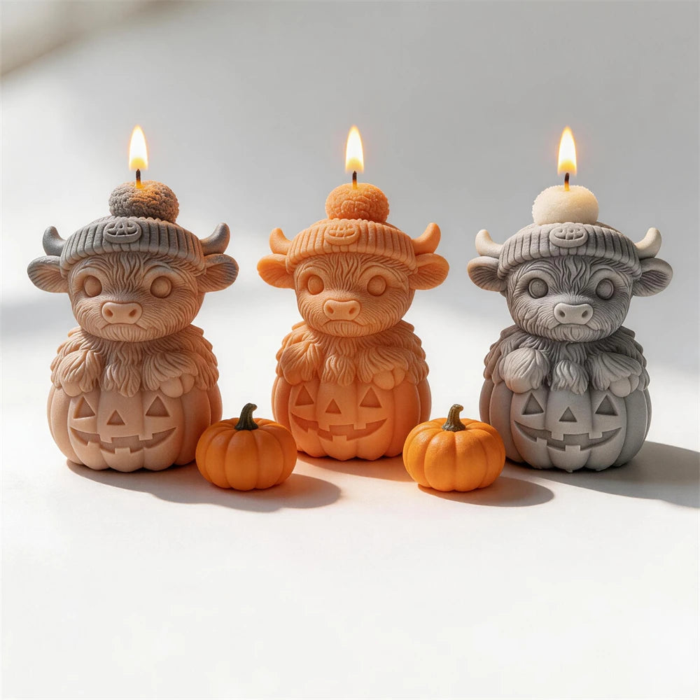 Three Highland cow jack-o'-lantern candle castings with knitted hats
