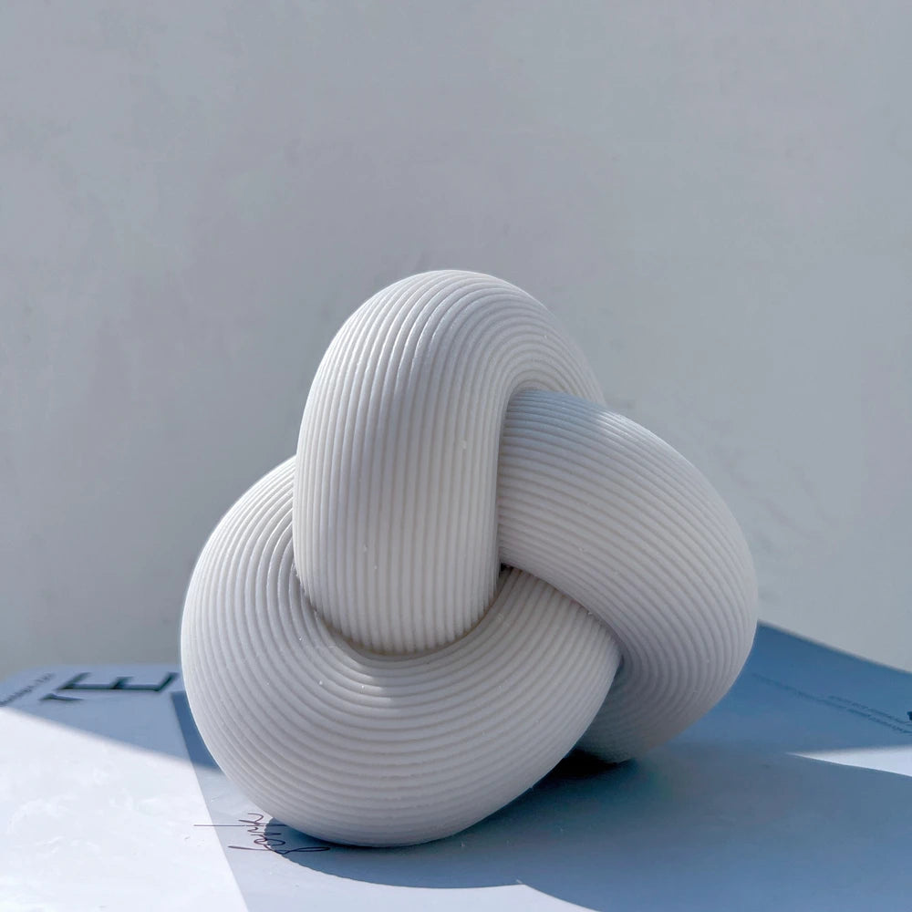 Angled view of gray knot candle showing curved ribbing