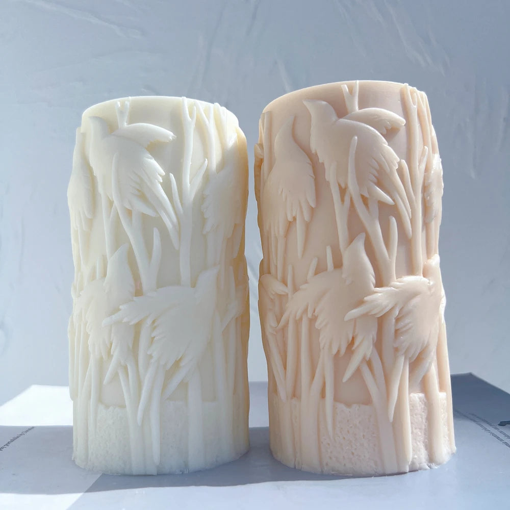 Two bird-relief pillar candle castings with tall reeds