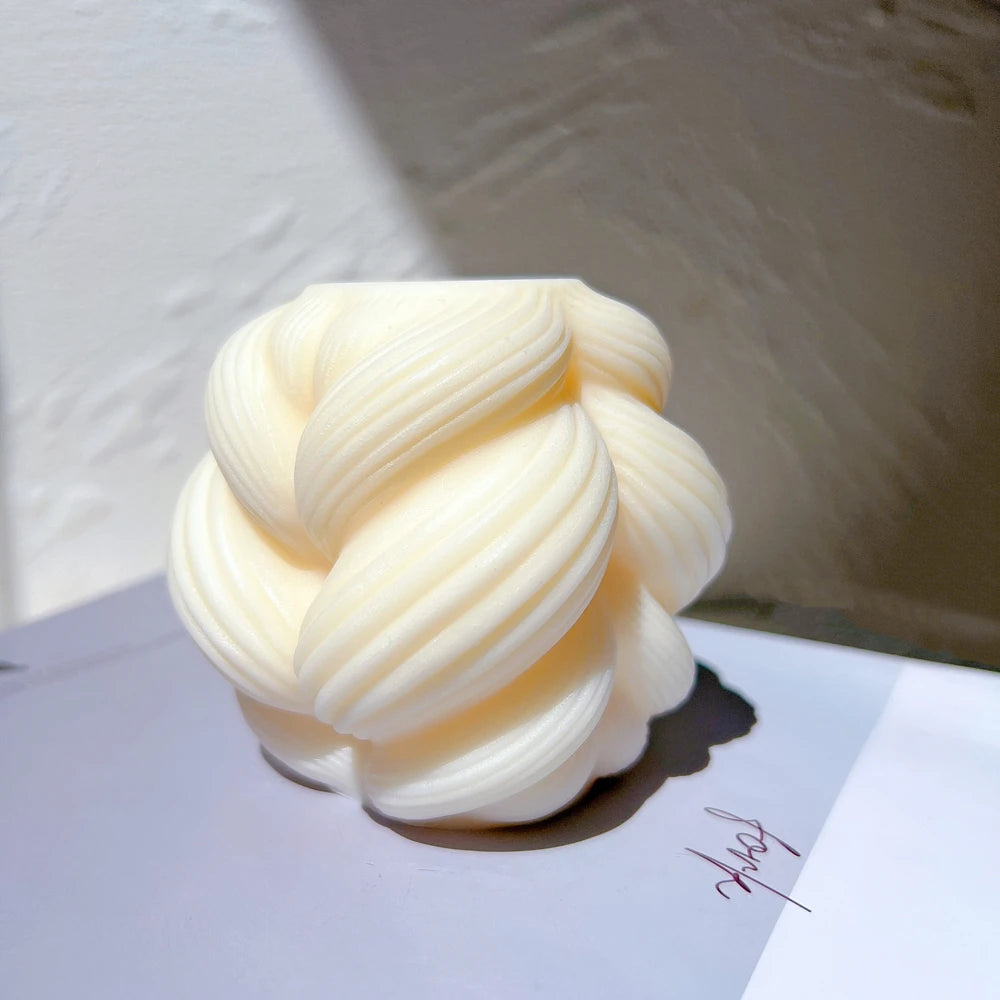 Small rounded braided-swirl figure with ribbed folds