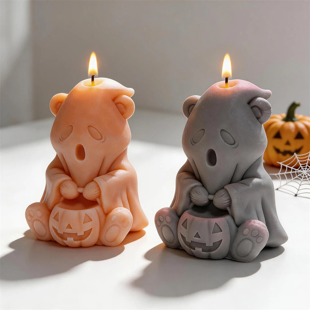 Two seated ghost bear candles displaying pumpkin faces and paw pads