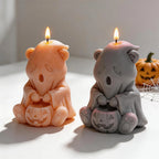 Two seated ghost bear candles displaying pumpkin faces and paw pads