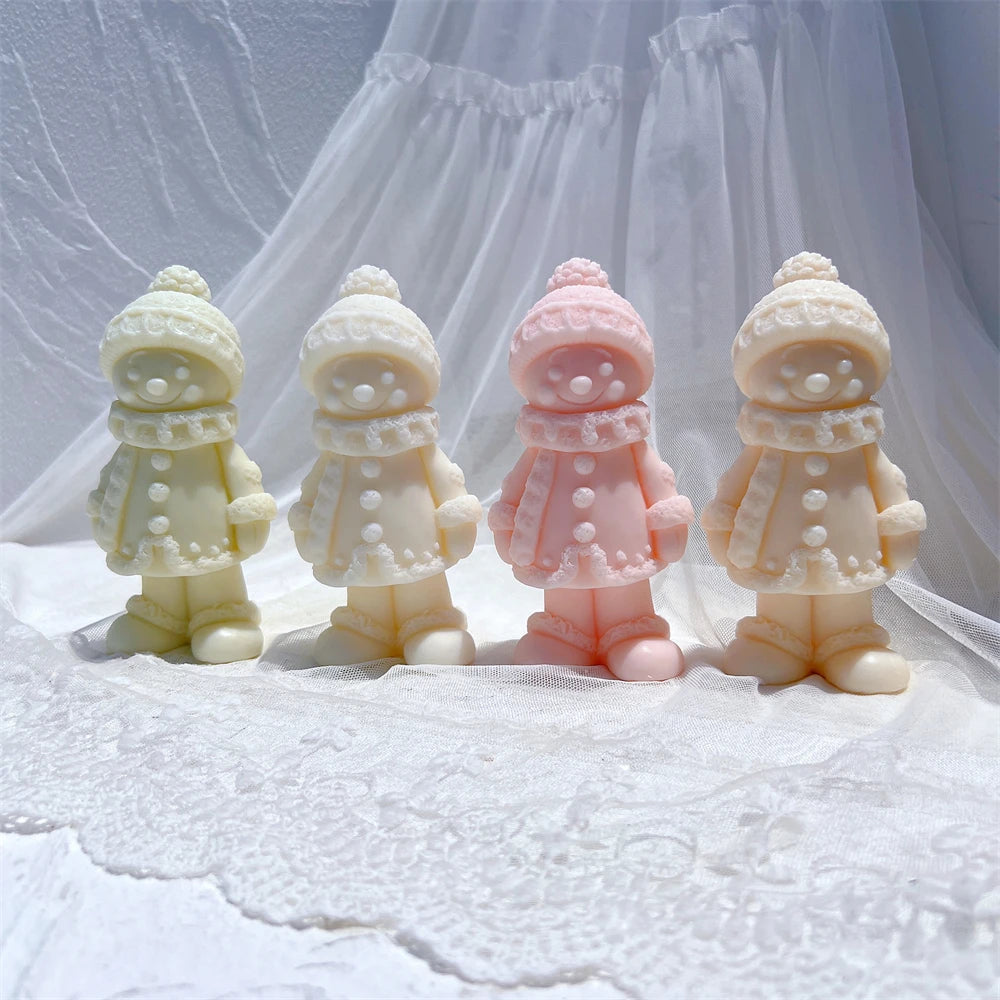 Four clothed winter figure castings with buttoned coats