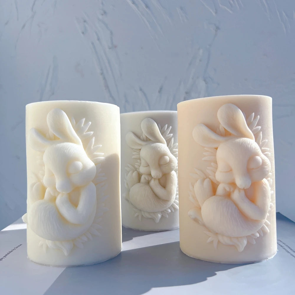 Angled view of cylindrical candles with seated rabbit reliefs
