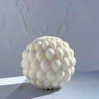 Cream round candle covered with overlapping teardrop scales