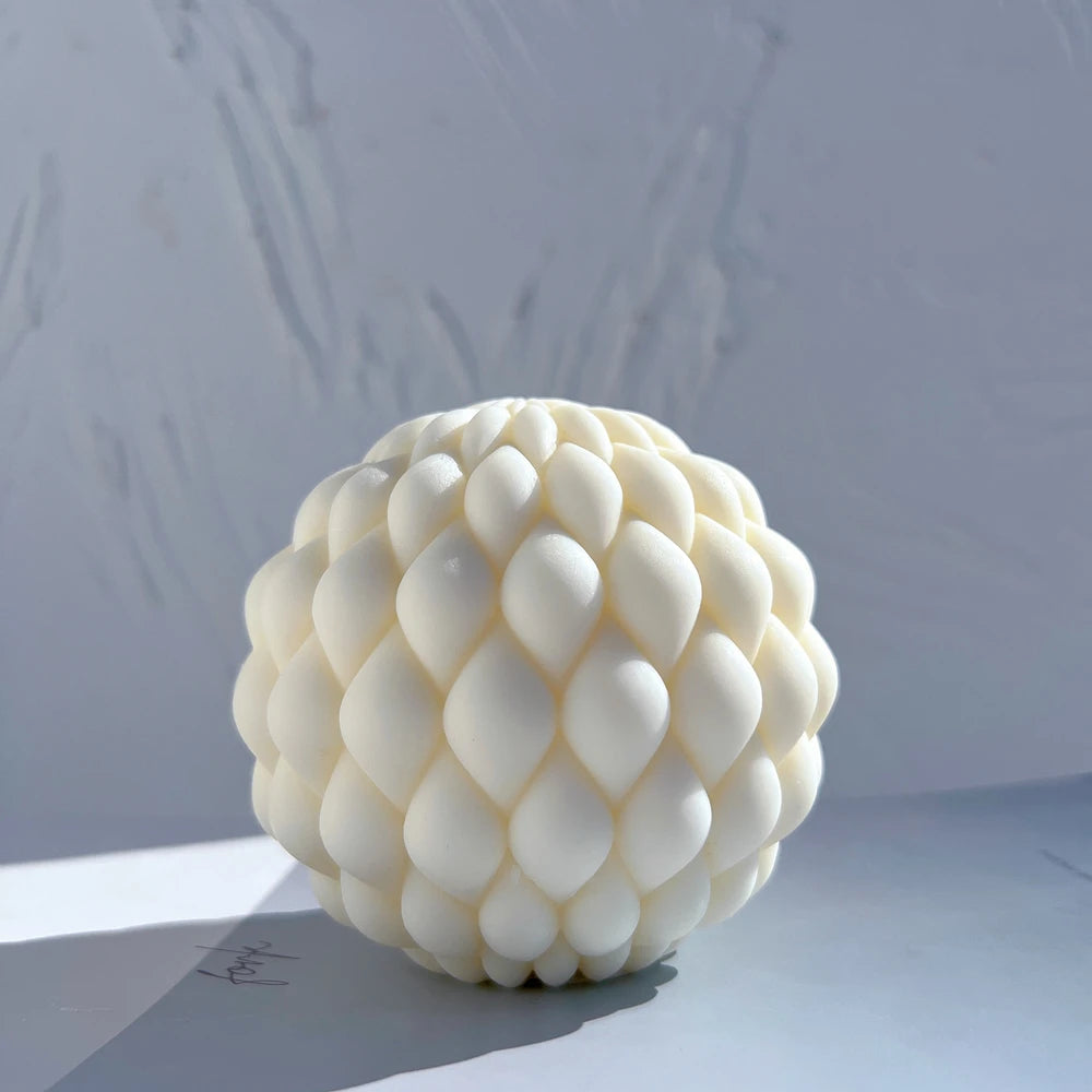 Cream round candle covered with overlapping teardrop scales