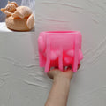 Pink sleeping-cat-and-basket silicone candle mold held in one hand