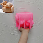 Pink sleeping-cat-and-basket silicone candle mold held in one hand