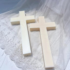 Two plain cross castings lying on textured white fabric