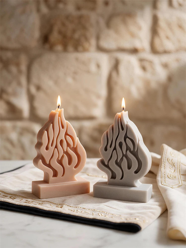 Pair of lit flame-motif sculptures beside decorative fabric on table