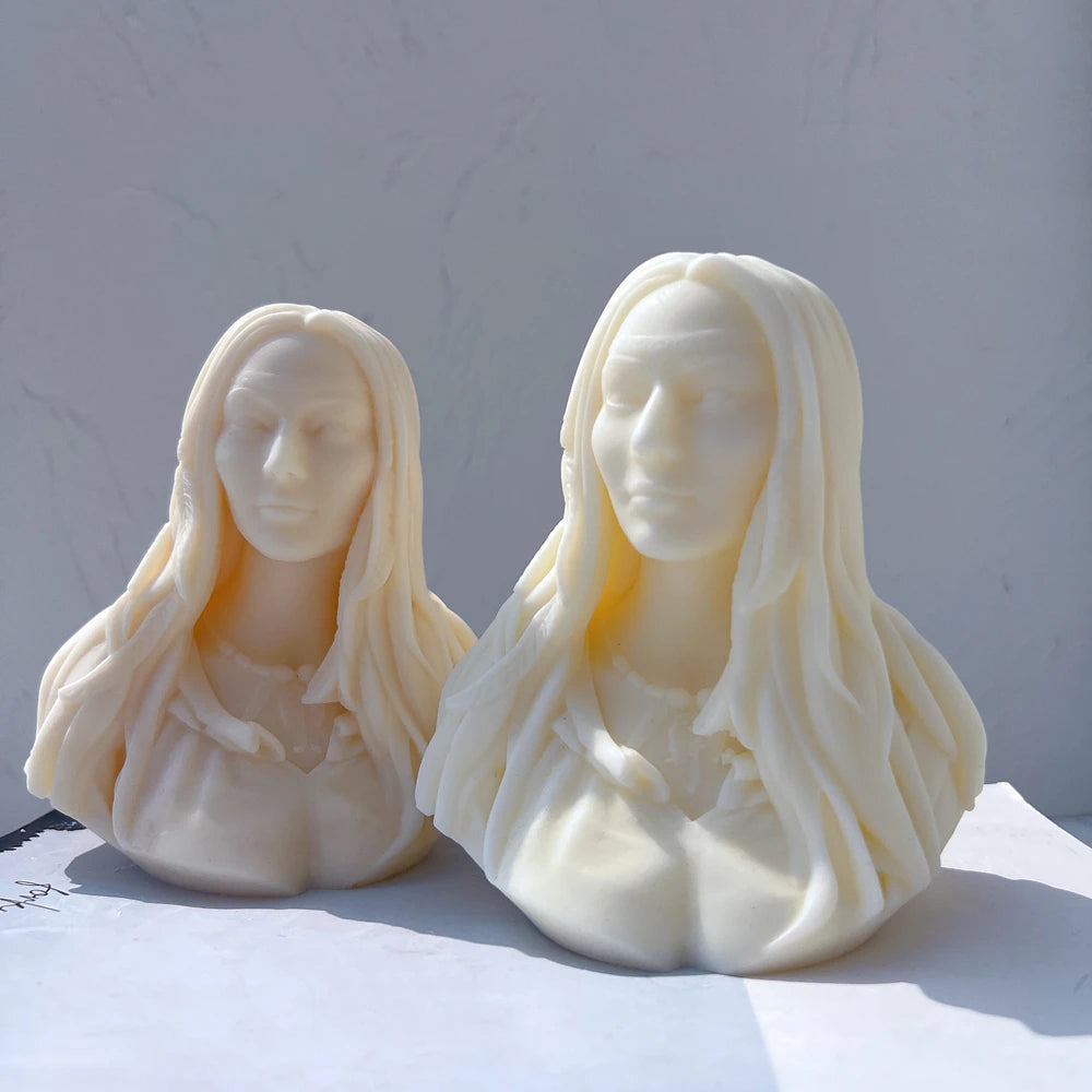 Two woman bust candle castings in warm light