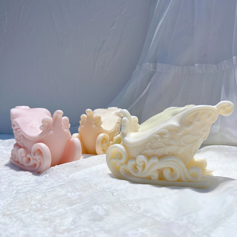 Cream and pink Christmas sleigh wax castings on white fabric