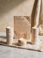 Rectangular Hebrew lettering plaque displayed beside decorative candles