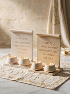 Two upright Hebrew scroll inscription plaques beside a row of decorative tealights