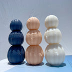 Front view of connected three-pumpkin candles with raised spiders