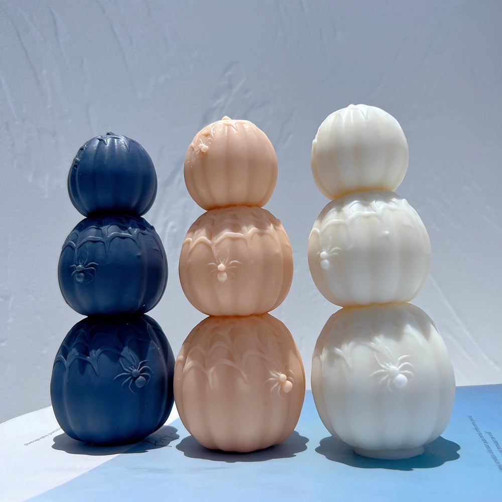 Front view of connected three-pumpkin candles with raised spiders