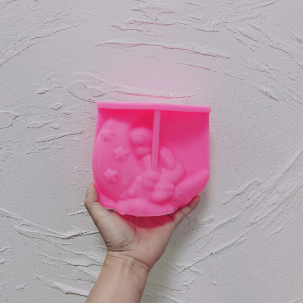 Pink silicone angel crescent moon mold held in a hand