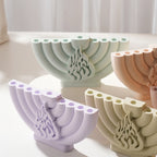 Close view of four curved nine-branched menorahs with central raised ornament
