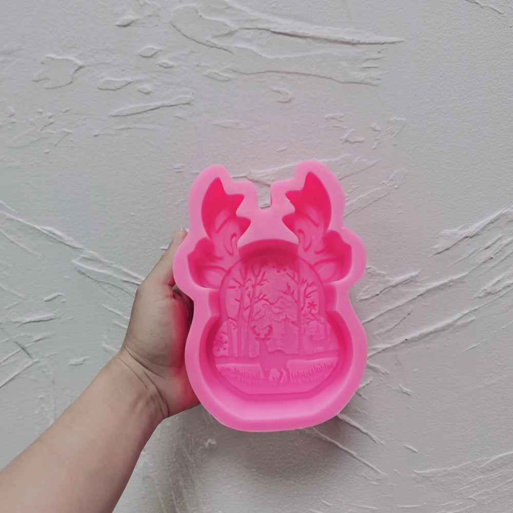 Pink antler-framed forest relief silicone mold held in one hand
