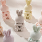 Pastel seated bunnies with flowers held in both paws
