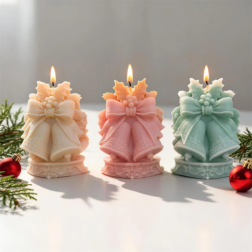 Three bell candles beside Christmas greenery and ornaments