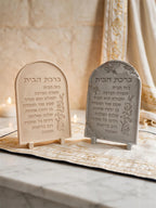 Close front view of two arched Hebrew lettering plaques and floral edges