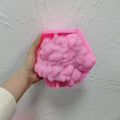 Pink silicone lion-head mold held sideways, revealing detailed negative mane relief