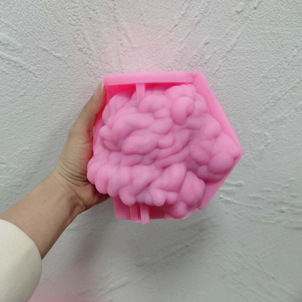 Pink silicone lion-head mold held sideways, revealing detailed negative mane relief