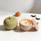 Knitted pumpkin container and matching lid beside an open candle-filled example