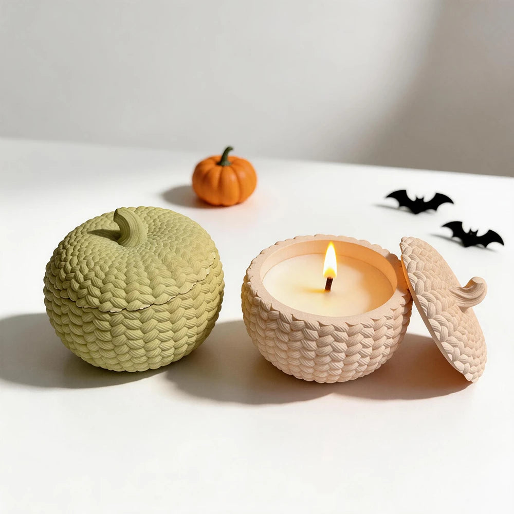 Knitted pumpkin container and matching lid beside an open candle-filled example