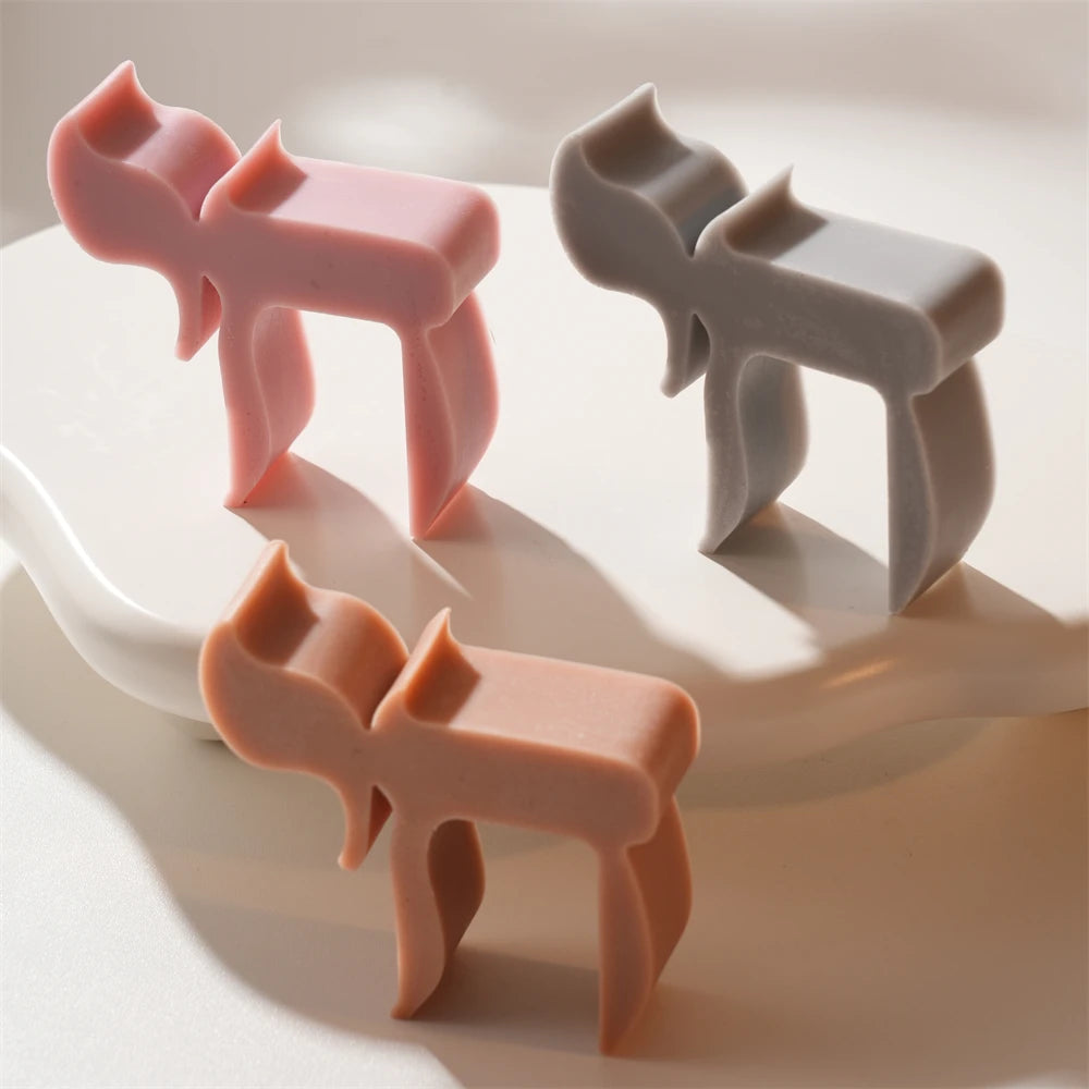 Three pink orange and gray Chai symbol castings with freestanding supports