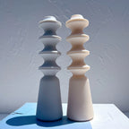 Blue and peach stacked-disc candle forms standing side by side