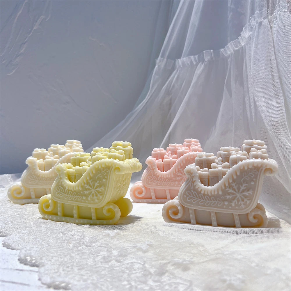 Two Christmas present sleigh candles with detailed carved side panels