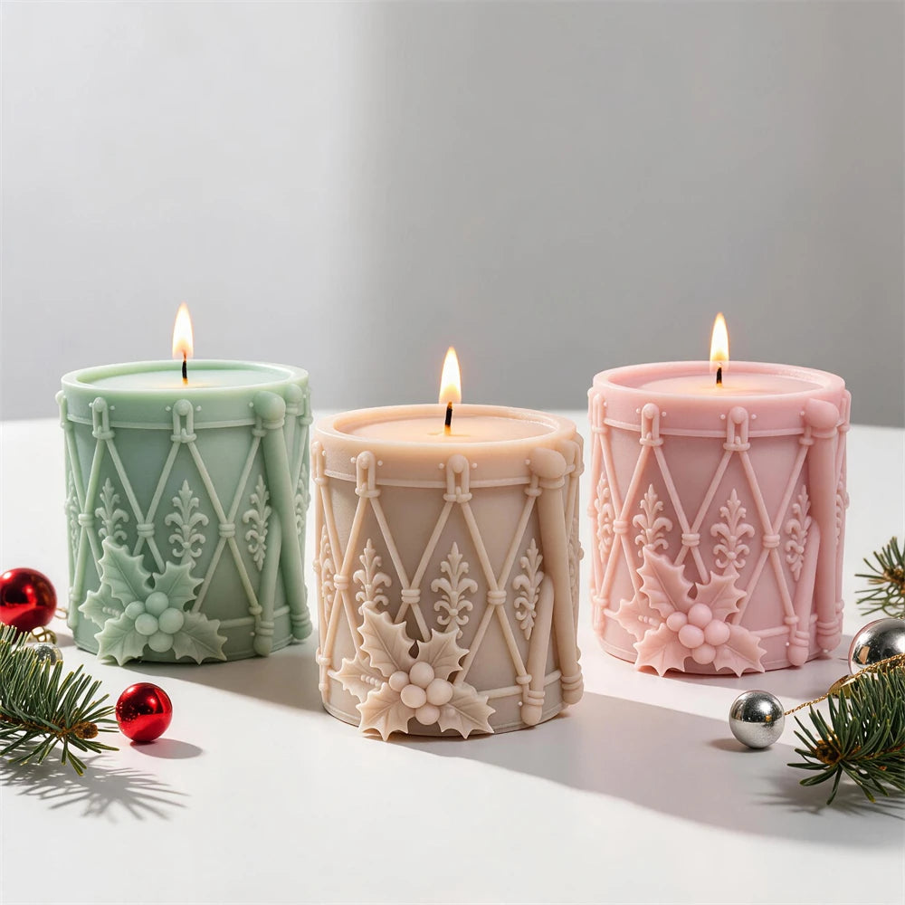 Green cream and pink drum-shaped candles with diagonal lacing and holly