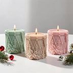 Green cream and pink drum-shaped candles with diagonal lacing and holly