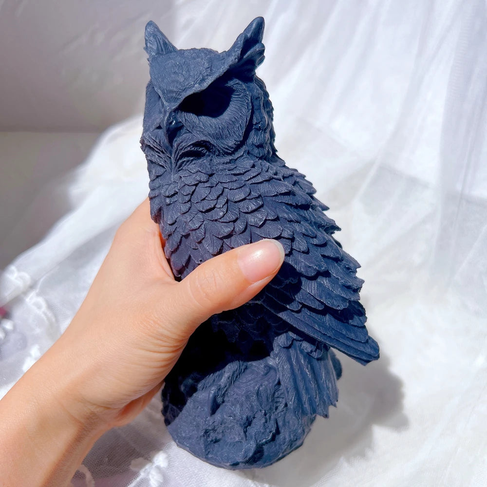 Dark owl casting held in a hand to show the sculpted form