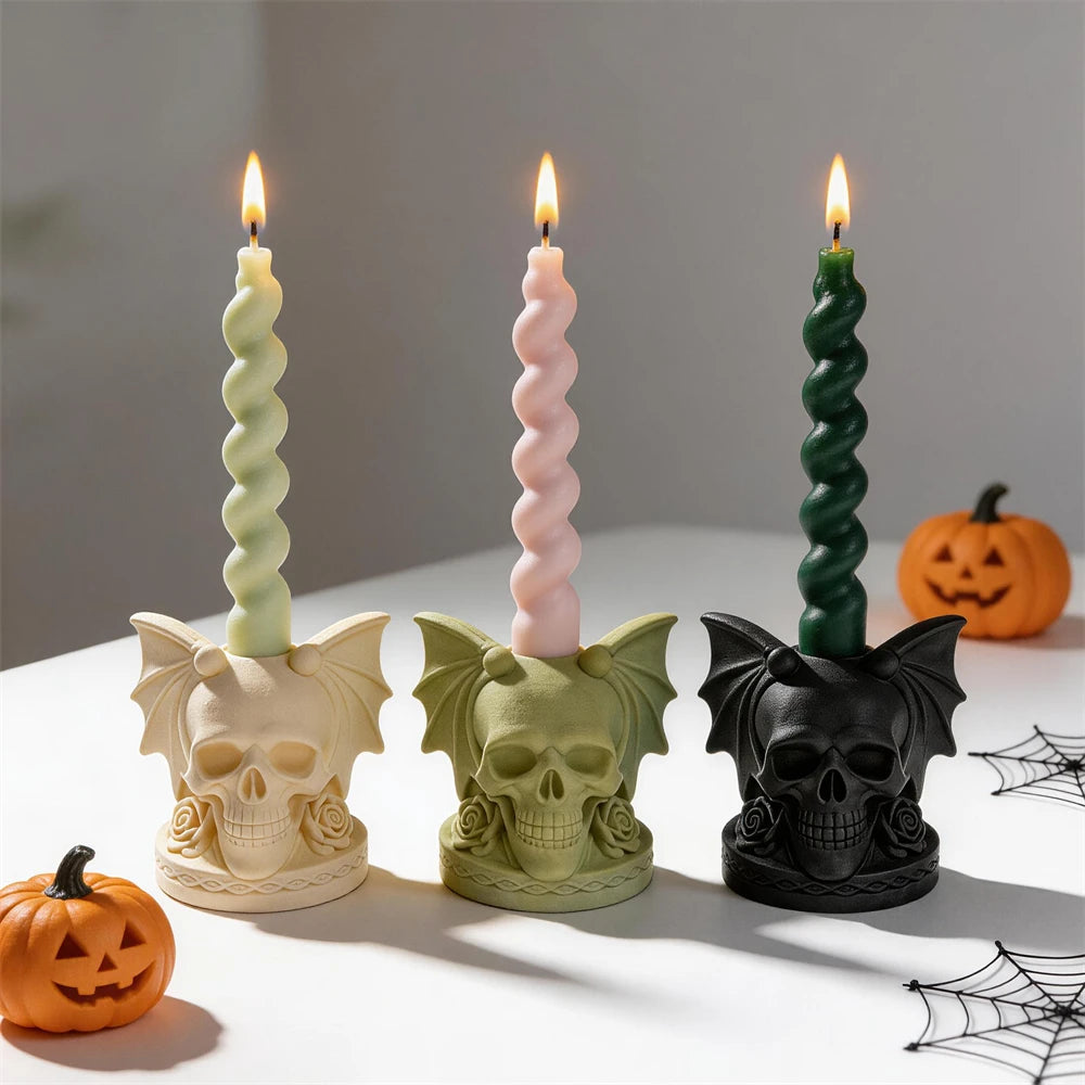 Bat-wing skull holders beside decorative pumpkins
