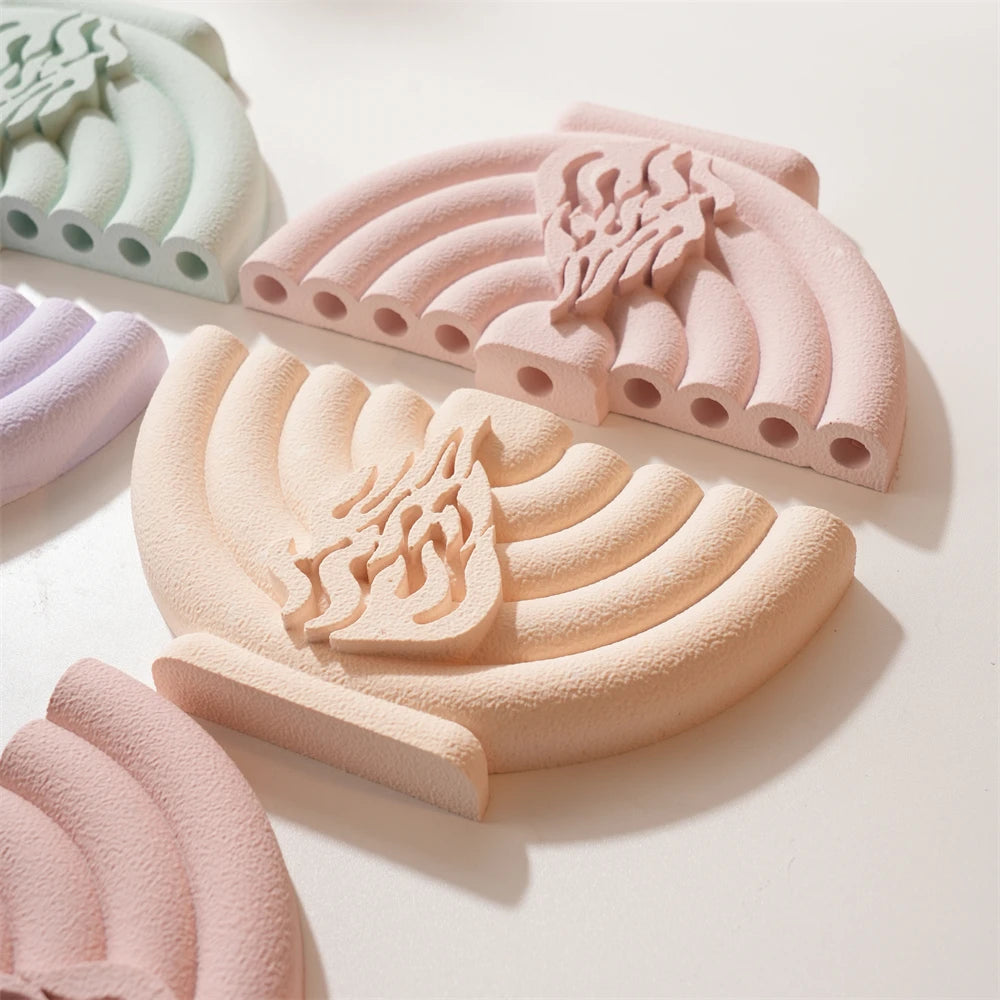 Cream and peach menorah castings laid flat to show curved branches and openings
