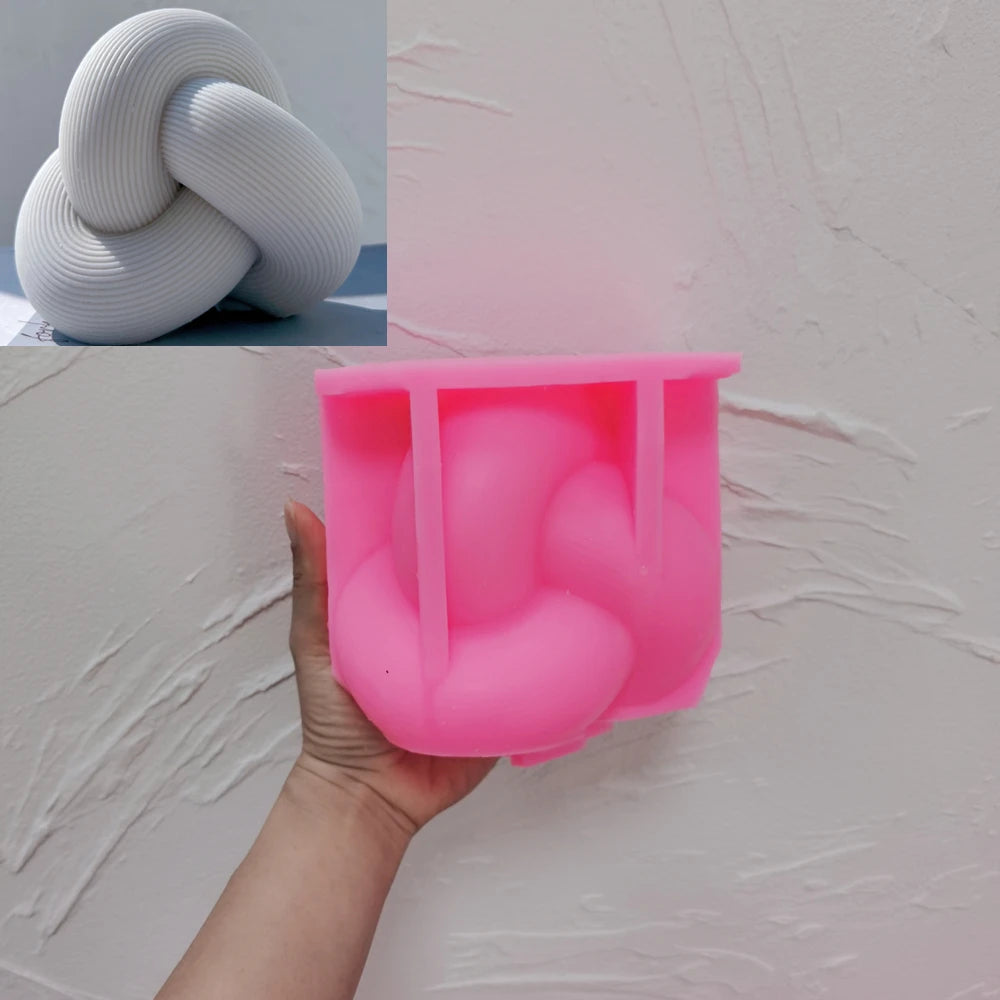 Pink silicone tube knot mold held beneath a casting example