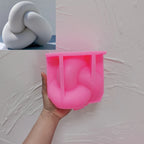 Pink silicone tube knot mold held beneath a casting example