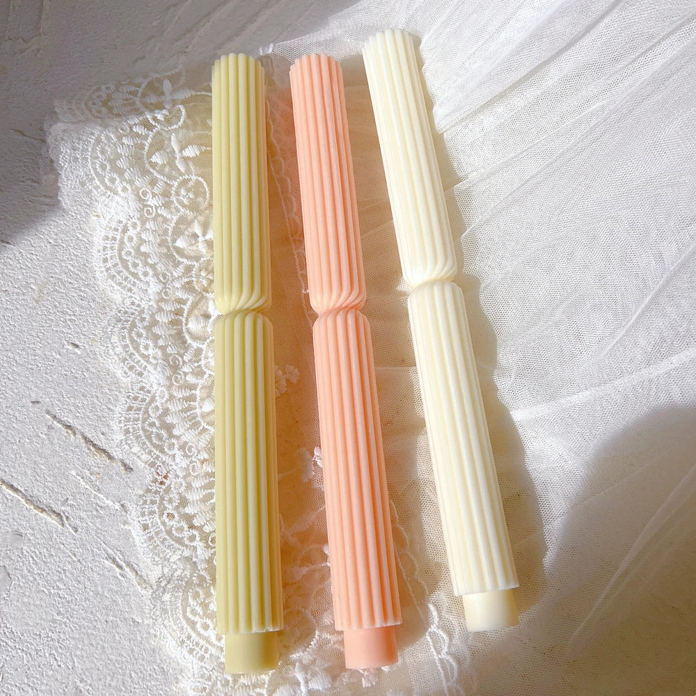 Straight ribbed tapers laid on a fabric surface