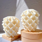 Two cream-colored sculptural candle castings with overlapping rounded petal relief