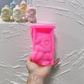Pink silicone winter owl mold held in a hand beside hat-and-scarf candle samples
