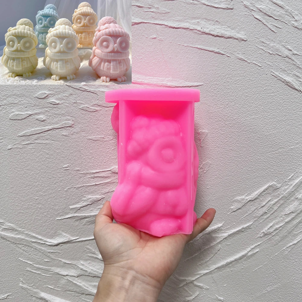 Pink silicone winter owl mold held in a hand beside hat-and-scarf candle samples